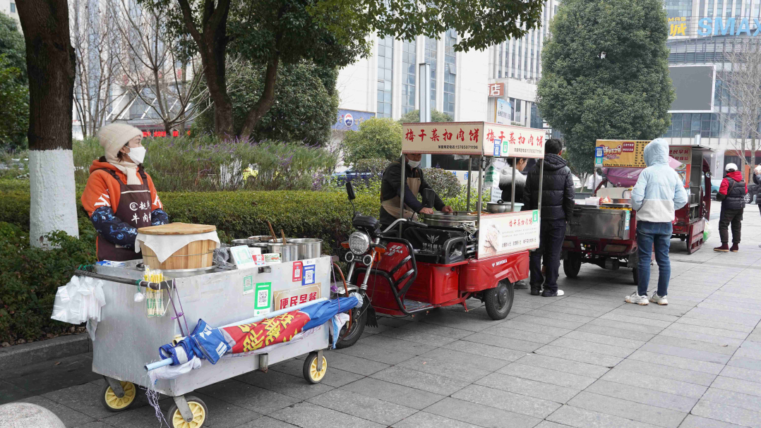 6便民早餐點聚攏各種早餐車，粉面、手抓餅、糯米飯等豐富的食物冒著熱氣。.jpg